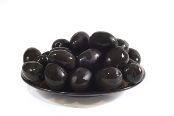 Plate of black olives on a white background, close up