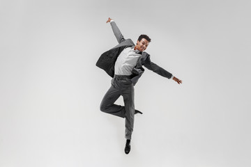 Happy businessman dancing in motion isolated on white studio background. Flexibility and grace in...