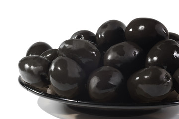 Plate of black olives on a white background, close up. Food