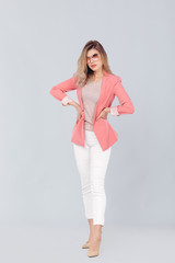 Obraz premium Full length portrait of attractive elegant blonde woman in pastel pink jacket posing in studio. woman dressed in trendy spring outfit