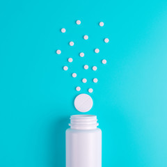 White pills, tablets in the glass bottle on a blue background.