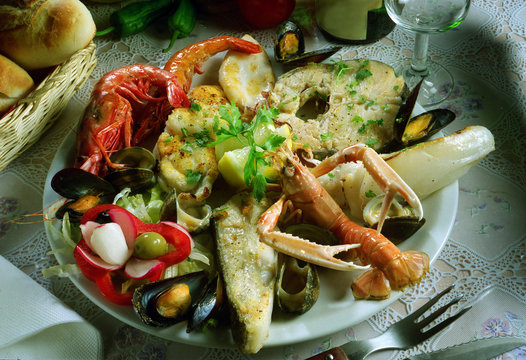Plato con una parrillada de pescado y marisco, con ensalada.