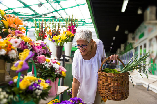 Charrming senior woman buying  flowers on  market