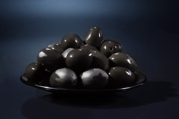 Group of black olives on a dark blue background