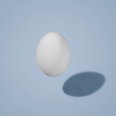 White egg in the air with a shadow, on a colored background. Morning mood.