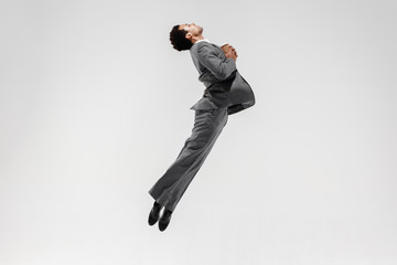 Happy businessman dancing in motion isolated on white studio background. Flexibility and grace in...