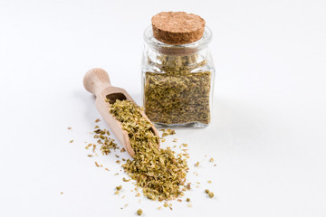 oregano herb in wooden scoop and jar on isolated on white background