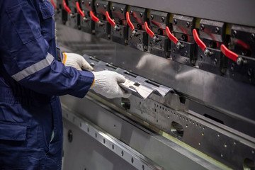 The technician operator use hydraulic bending machine. The sheet metal manufacturing process.