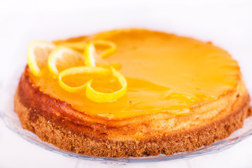 Lemon cheesecake on white background decorated with lemon zest close up