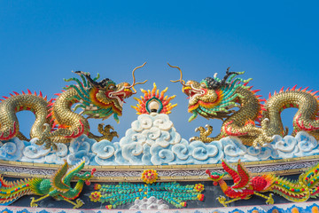 Beautiful large grimace dragons crawling on the decorative tile roof in Chinese temples. Colorful...