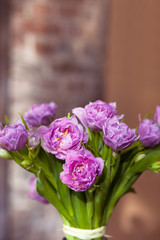 Bunch of pink spring flowers with green leaves at home, light beautiful purple tulips bouquet as nice romantic present from floral shop made by professional florist, vertical close up view copy space