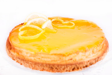 Lemon cheesecake on white background decorated with lemon zest close up