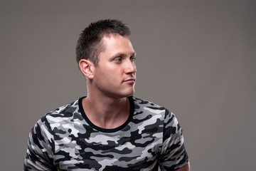 Confident handsome adult young muscular man looking away at copy space on gray background. 