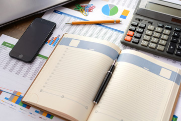 Open leather notebook, drawings, charts, phone, calculator, pencil and laptop on the desk in the office. Business and Finance.