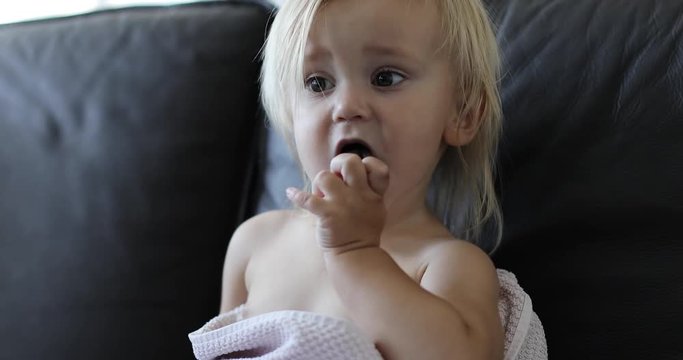Cute girl sitting on the couch and gnaws cork.