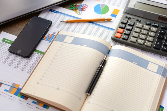 Open leather notebook, drawings, charts, phone, calculator, pencil and laptop on the desk in the office. Business and Finance.