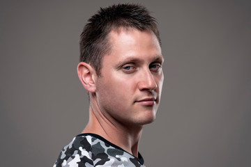 Portrait of indifferent cool young man looking at camera with skeptical expression over gray background. 