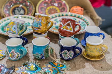 Variety of Colorfully Painted Ceramic Pots in an Outdoor Shopping Market. pottery in the shop window. Clay cups and plates