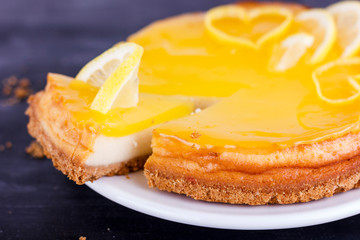 Lemon cheesecake on black background decorated with lemon zest close up