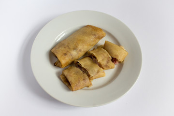 Two fried pancakes with ham and cheese filling on a white plate, white, gray background