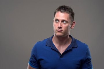 Fototapeta premium Portrait of confused young adult man looking up at copy space over gray background. 