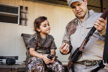Man teaching girl (6-7) how to use gun 