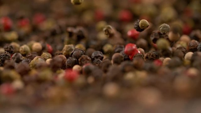 SLOW MOTION, MACRO, DOF: Fragrant colorful pepper seeds fall and bounce inside a pan. Aromatic spices and herbs bouncing around a container that falls on the kitchen counter. Pepper mix is toasting.