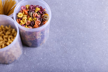 Multicolored pasta with the addition of natural vegetable dye. In a jar on a concrete table. Top view, copy Space.