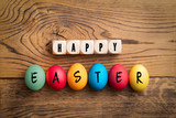colored eggs and cubes with letters forming the merssage "happy easter" on wooden background 