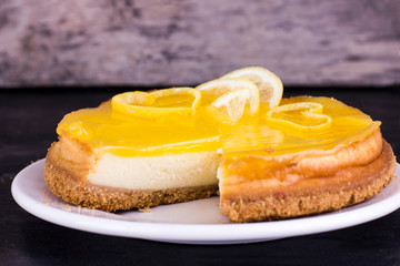Lemon cheesecake on black background decorated with lemon zest close up