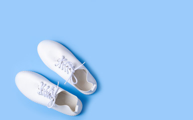 Pair of white sneakers on color background, flat lay, top view