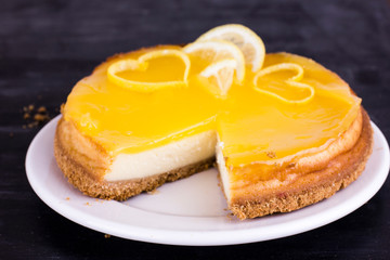 Lemon cheesecake on black background decorated with lemon zest close up