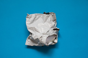 Damaged polyethylene envelope on blue background. Plastic Postal Mailing Bags