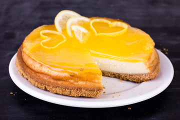 Lemon cheesecake on black background decorated with lemon zest close up
