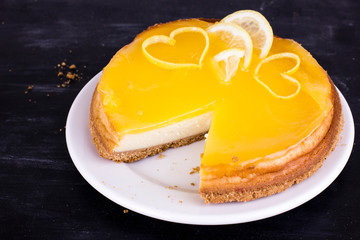 Lemon cheesecake on black background decorated with lemon zest close up