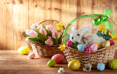 Easter composition with bunny in basket, spring flowers and colorful Easter eggs .