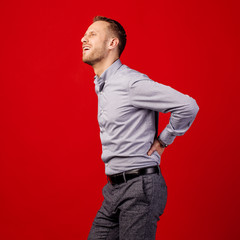 young bearded man having a back pain  over red background