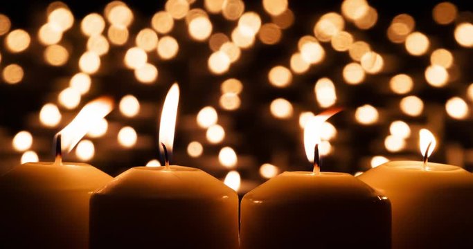 Dramatic Candle Scene. Four large candles close up against the background of many small lights. Air slowly rocking fire. Filmed at a speed of 120fps