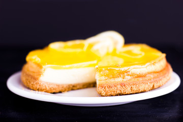 Lemon cheesecake on black background decorated with lemon zest close up