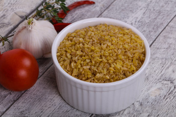 Raw bulgur in the bowl with tomatoes and garlic