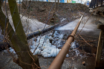 Water pressure from a large pipe over the river, in winter