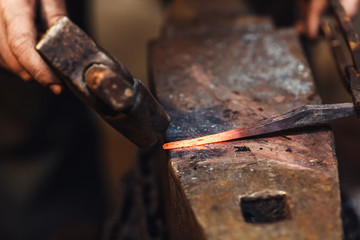 blacksmith makes an artistic forging of hot metal on the anvil.