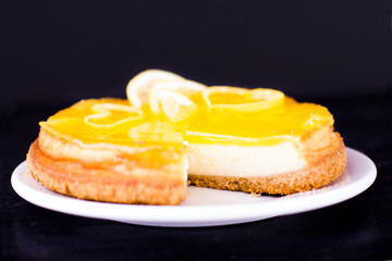 Lemon cheesecake on black background decorated with lemon zest close up