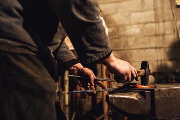 blacksmith makes an artistic forging of hot metal on the anvil.
