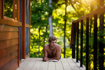 Young man reading book on porch 