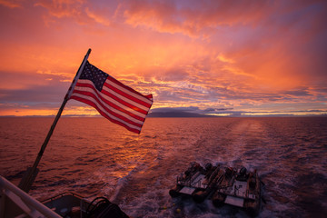 American flag in front of a beautiful ocean sunset landscape