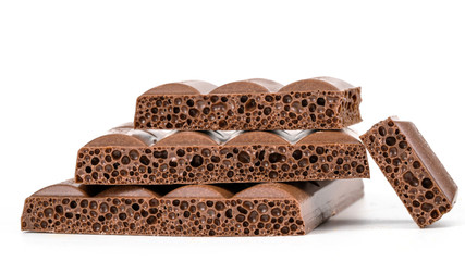 Close up of chocolate pieces stack and chocolate syrup on white background