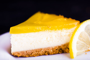 Lemon cheesecake on black background decorated with lemon zest close up