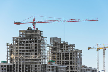 View of a residential complex under construction with high cranes. Large-scale building of the city