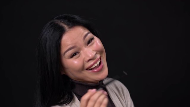 Smiling Asian touches her face with pen